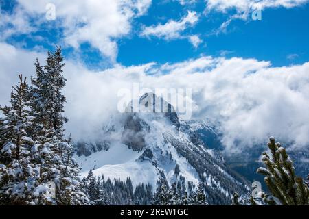 Atemberaubender Blick auf den felsigen und steilen Berg Aggenstein in den Alpen im Winter, umgeben von Wolken und herrlicher und friedlicher Schneelandschaft Stockfoto