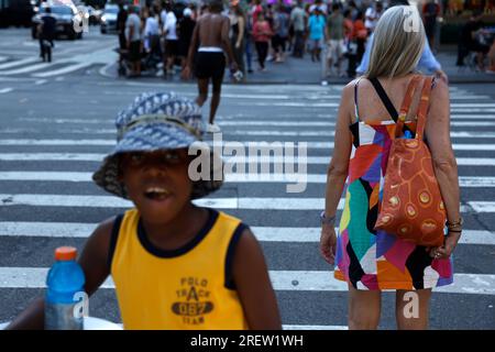 Ein Junge sieht zu, wie eine Frau am 29. Juli 2023 in New York City, USA, die Straße überquert. In den letzten Tagen erlebte die Stadt Temperaturen Mitte der neunziger Jahre, wobei die hohe Luftfeuchtigkeit den Index „reales Gefühl“ in dreistellige Zahlen drückte. Ab Sonntag wird eine Kaltfront die Temperaturen voraussichtlich auf die 80er Jahre drücken und die Luftfeuchtigkeit verringern. (Foto: John Lamparski/Sipa USA) Guthaben: SIPA USA/Alamy Live News Stockfoto