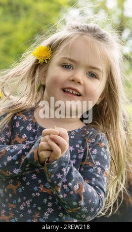 Ein lächelndes blondes Mädchen mit einer Blume im Haar Stockfoto