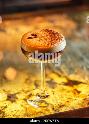 Glas mit alkoholischem Espresso, martini-Cocktail mit Kaffeebohnen und Kakaopulver auf weißem Schaum, serviert an der Theke in der Bar Stockfoto