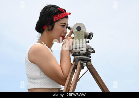 Hübsche asiatische Vermessungsfrau oder Ingenieurin, die mit Theodolith-Transitgeräten auf einer Baustelle im Freien arbeitet. Stockfoto