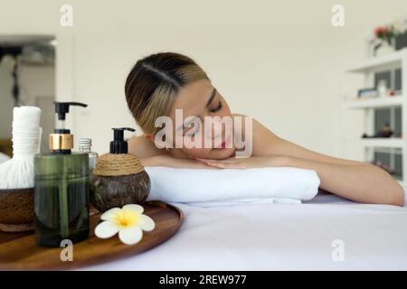 Ganzheitliches Luxus-Wellness-Erlebnis. Eine ruhige Frau, die sich gemütlich in einem beruhigenden Spa-Ambiente zurücklehnen kann, umgeben von Elementen, die Ruhe fördern. Stockfoto