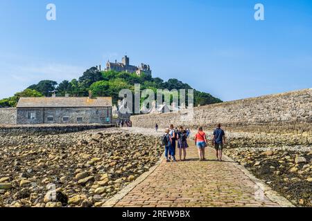 14. Juni 2023: Marazion, Cornwall, Großbritannien - Besucher, die an einem wunderschönen Sommertag auf dem Damm zum St. Michael's Mount spazieren. Stockfoto