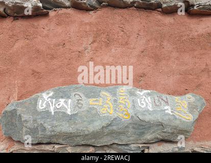 Mani-Stein an der Wand. Stein mit tibetischem Schriftzug. Stockfoto