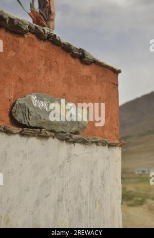 Mani-Stein an der Wand. Stein mit tibetischem Schriftzug. Stockfoto