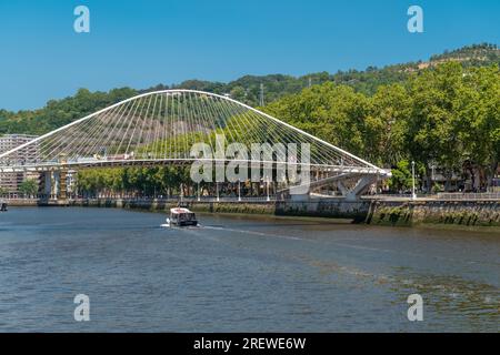Zubizuri-Brücke, auch Campo Volantin-Brücke genannt. Ist eine Fußgängerbrücke mit Bögen über den Nervion in Bilbao, Spanien. Leute kommen vorbei. Stockfoto