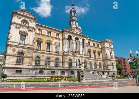 Wunderschönes Rathausgebäude der Stadt Bilbao, im Barockstil erbaut. Vor dem Gebäude befindet sich der Fluss Nervion. Leute kommen vorbei. Stockfoto