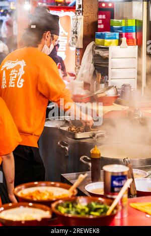 Nahaufnahme eines Küchenchefs, inmitten von aufsteigendem Dampf und überfüllter Arbeitsplatte, im Kinryu Ramen Restaurant in Dotonbori, Osaka am Abend. Stockfoto