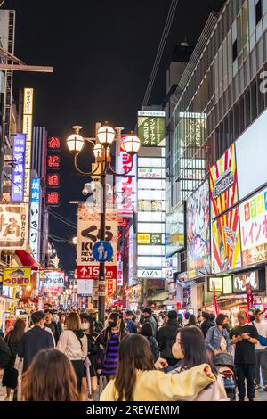 Die Touristenmassen laufen nachts durch die beliebte Dotonbori Straße in Osaka unter den hellen Lichtern und Neonschildern für die vielen Restaurants Stockfoto