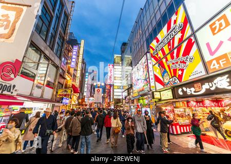 Die Touristenmassen laufen nachts durch die beliebte Dotonbori Straße in Osaka unter den hellen Lichtern und Neonschildern für die vielen Restaurants Stockfoto