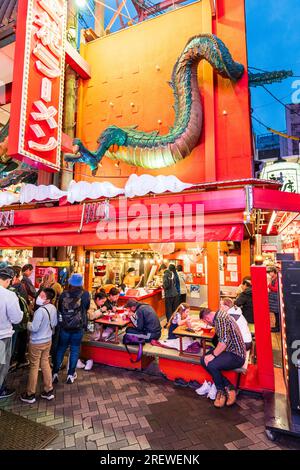 Das sehr beliebte Restaurant Kinryu Ramen in Dotonbori, Osaka. Die Gäste sitzen an kleinen Tischen vor der Theke und essen abends Nudeln. Stockfoto