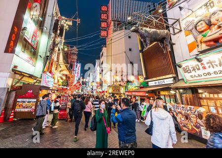 Dotonbori, das Unterhaltungsviertel von Osaka am Abend. Die Straße ist voller Menschenmassen mit Restaurants und hell beleuchteten Schildern auf beiden Seiten. Stockfoto