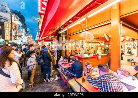 Das sehr beliebte Restaurant Kinryu Ramen in Dotonbori, Osaka. Die Gäste sitzen an kleinen Tischen vor der Theke und essen abends Nudeln. Stockfoto