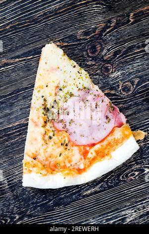 Eine Pizza gefüllt mit Schinken, Käse und anderen Zutaten, preiswertes Fast Food, ungesundes Essen Stockfoto