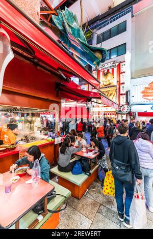 Das sehr beliebte Restaurant Kinryu Ramen in Dotonbori, Osaka. Die Gäste sitzen an kleinen Tischen vor der Theke und essen abends Nudeln. Stockfoto