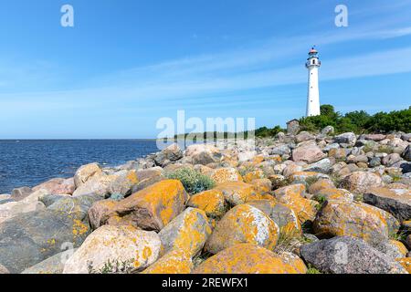 Spektakulärer felsiger Strand mit Kihnu Leuchtturm im Hintergrund auf der Insel kihnu in der ostsee, an einem schönen sonnigen Sommertag, estland Stockfoto