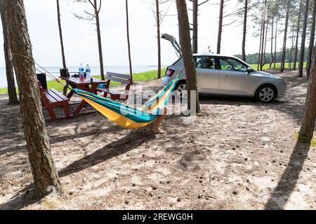 Touristen entspannen in einer Hängematte in einem Wald in der Nähe von Sandstrand an einem sonnigen Sommertag auf der Insel Kihnu, Estland Stockfoto