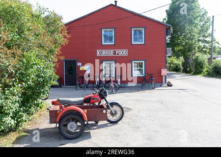 Altes russisches Motorrad (Motorrad) mit Beiwagen vor einem traditionellen Holzhaus auf der Insel kihnu in der ostsee, estland Stockfoto