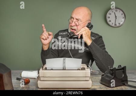 Oldtimer-Autor-Journalist bei der Arbeit. Schreibtisch mit Telefon und Schreibmaschine. Redakteur Stockfoto