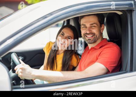 Fröhliche Millennials-Paare, die vom Autofenster lächeln Stockfoto