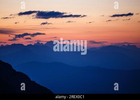 Bergprofile, Silhouetten, Schichten im Morgengrauen. Rötlicher Himmel. Profile der Dolomitspitzen am Horizont. Italienische Alpen. Europa. Stockfoto