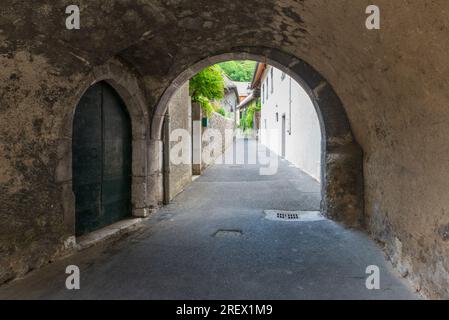 Enge Gassen der alten französischen Stadt in der Provence. Steinbogen und Wände, alte Türen und Blumen an den Fenstern Stockfoto