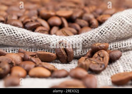 Kaffeebohnen, aus denen man ein heißes belebendes Kaffeegetränk zubereiten kann, braune Kaffeebohnen, die auf einem Tisch aus Brettern liegen Stockfoto