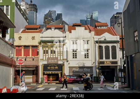 Renovierte alte Einkaufshäuser in South Bridge Road, Chinatown, Singapur, beleuchtet von Abendlicht und dunklen Wolken; Blick von der angrenzenden Temple Street Stockfoto