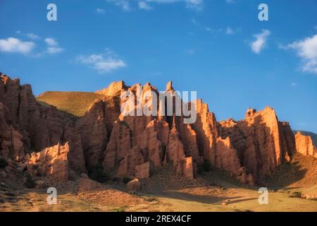 Trakt Zhaman uy in den Bergen Kasachstans. Fantastische rote Tonreste am blauen Himmel. Stockfoto