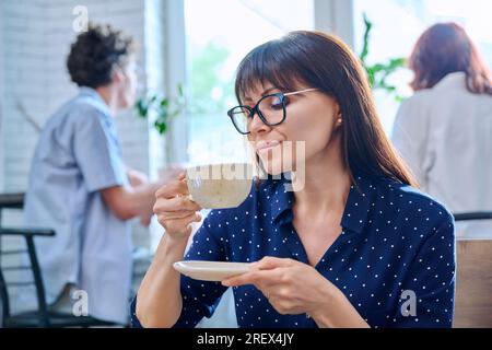 Entspannte Frau mittleren Alters, die duftenden Kaffee im Café genießt Stockfoto