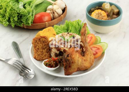 Nasi Tutug Oncom, Reis mit fermentierter Erdnuss, serviert mit gebratenem Hühnchen Ayam Goreng und Sayur ASEM. Traditionelle Sundanesische Küche, Indonesische Küche. Stockfoto