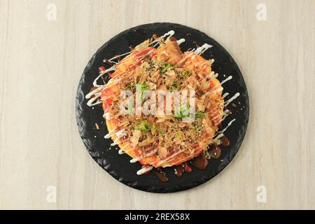 Okonomiyaki mit japanischem, herzhaftem Eierkuchen auf schwarzem Schieferteller Stockfoto