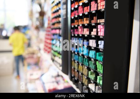 Selektiver Fokus auf Regal mit Buntstiften für Pastelltöne, die den Hintergrund verschwommener Leute beim Einkaufen im Schreibwarenladen der Schule darstellen. Kreatives Hobby. Stockfoto