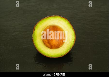 Halber Avocado mit Samen auf schwarzem Hintergrund - gesundes Superfood Stockfoto