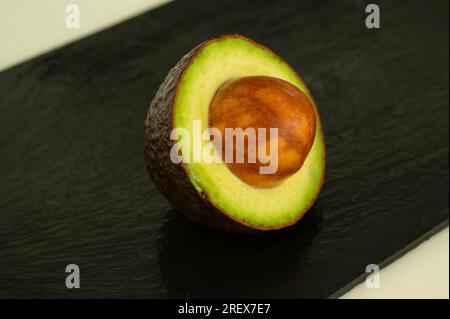 Halber Avocado mit Samen auf schwarzem Hintergrund - gesundes Superfood Stockfoto