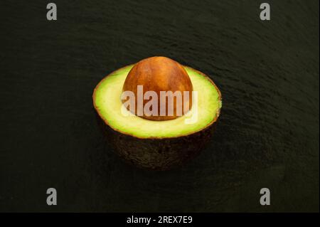 Halber Avocado mit Samen auf schwarzem Hintergrund - gesundes Superfood Stockfoto