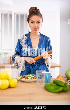 Unzufriedene Frau, die in der Hausküche steht, mit einer Nadel in den Händen Stockfoto