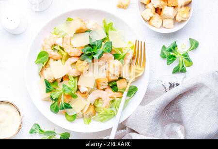 Gourmet-Caesar-Salat mit Garnelen, Eisberg und Salat, Croutons, Parmesan und caesar-Dressing. Weißer Tischhintergrund, Draufsicht Stockfoto