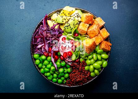 Vegane buddha-Schüssel mit roter Quinoa, gebratenem Tofu, Avocado, Edamambohnen, grünen Erbsen, Rettich, Kohl, Granatäpfel und Sesamsamen mit Sojasauce. Heilen Stockfoto