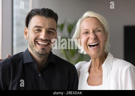 Fröhliche, stolze rentnermutter, die einen fröhlichen erwachsenen Sohn umarmt Stockfoto