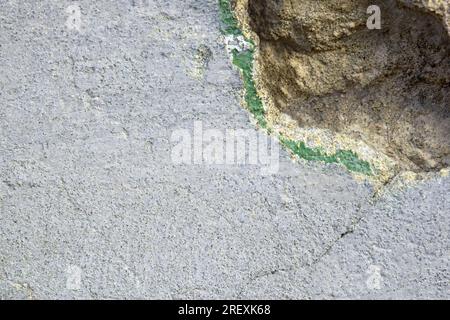 Hintergrund der alten Wand mit zusammengefallenem Putz und Riss. Struktur der schäbigen verwitterten Gebäudeoberfläche. Zerstörte Wand mit heruntergefallenem Gips. Bohrung im Stockfoto