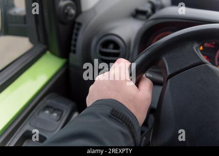 Die Hand eines Mannes auf dem Lenkrad eines Autos. Nahaufnahme. Lenkung. Ausgewählter Fokus. Stockfoto