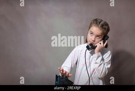 Ruf in die Vergangenheit. Das Teenager-Mädchen wählt eine Nummer auf einem alten Telefon. Retro-Porträt eines Mädchens. Stockfoto