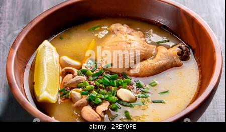 Peruanische Caldo de gallina Hühnernudel-Suppe aus der Nähe in einem Teller auf dem Tisch. Vertikale Ansicht von oben Stockfoto