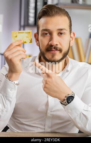 Geschäftsmann zeigt Kreditkarten aus Plastik, Werbung für Geldtransfer ohne Bargeld, Einkäufe im Internet, Rabatte, Bestellung über das Internet. Freiberufler im Büro. Vertikal Stockfoto