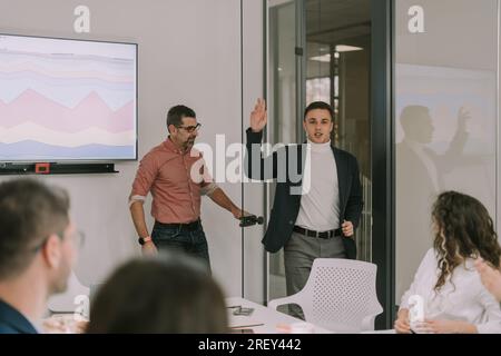 Der junge Mann kommt zu spät. Ich bin gerade in den Sitzungsraum gegangen. Er sagt Hallo zu allen da drin Stockfoto