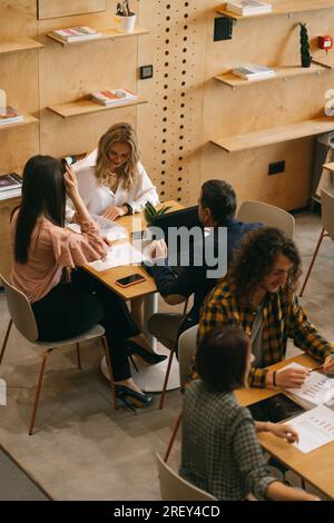 Bild oben: Generationenübergreifende Mitarbeiter des Unternehmens, die im Café des modernen Co-Arbeitsbereichs zusammenarbeiten Stockfoto