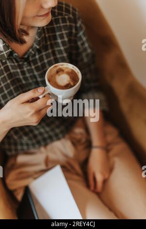 Nahaufnahme einer Frau, die eine Tasse Kaffee hält und lächelt Stockfoto