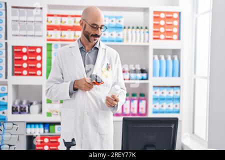 Junger hispanischer Mann Apotheker Scannen Pillen Flasche in der Apotheke Stockfoto