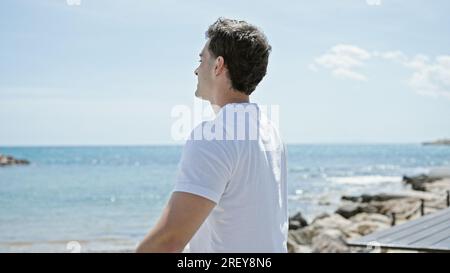 Junger lateinamerikanischer Mann atmet mit offenen Armen am Strand Stockfoto